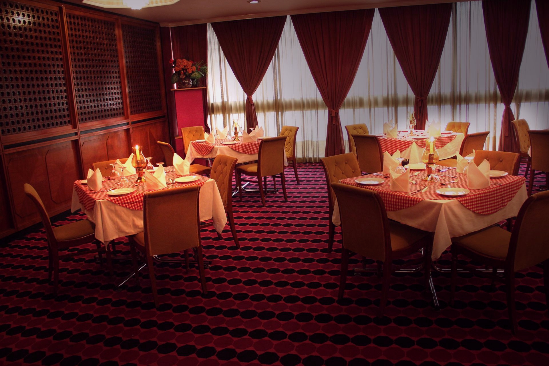 A photo of a dining room in a restaurant with several tables with set candles and cutlery