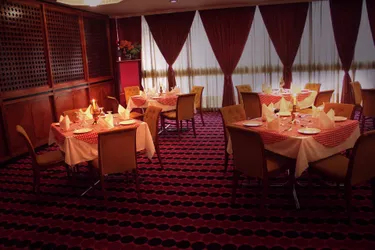 A photo of a dining room in a restaurant with several tables with set candles and cutlery